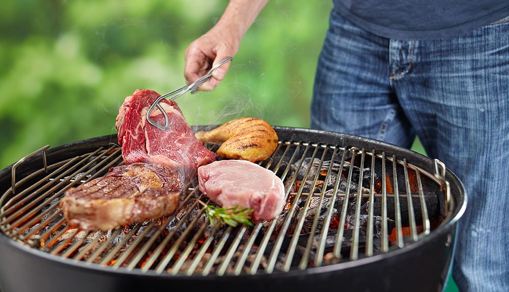 Ribeye wird am Holzkohlengrill gewendet